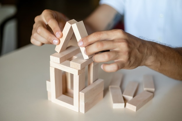 Cerca de las manos de un arquitecto masculino haciendo un modelo de casa. El hombre arquitecto trabaja en la oficina.