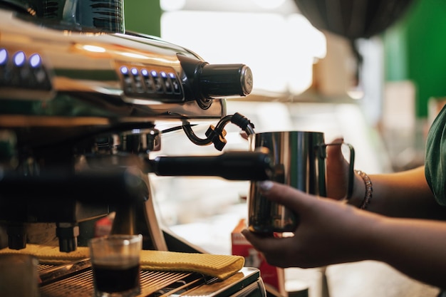 Cerca de las manos del barista preparando café para el cliente en la cafetería.