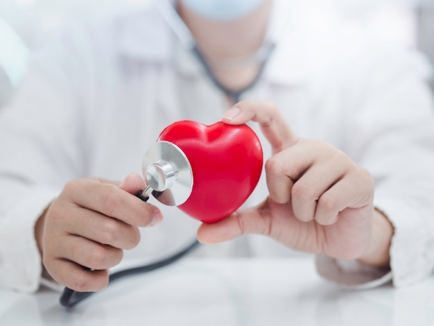 Cerca de las manos de la doctora examinando el corazón con un estetoscopio