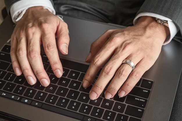 Cerca de las manos del empresario escribiendo en el teclado de la computadora