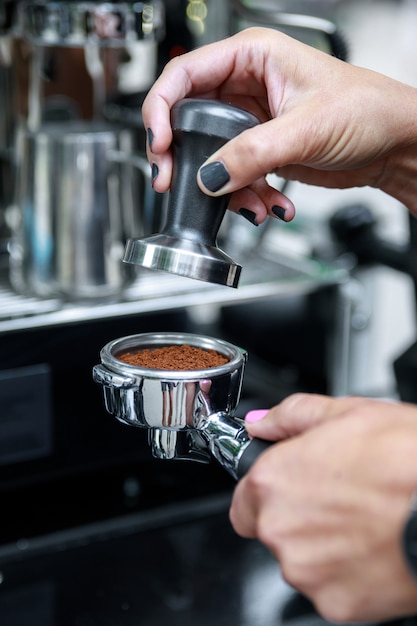 Cerca de manos femeninas. Barista está haciendo café.