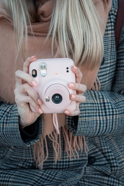 Cerca de manos femeninas con cámara de imagen rosa Instax