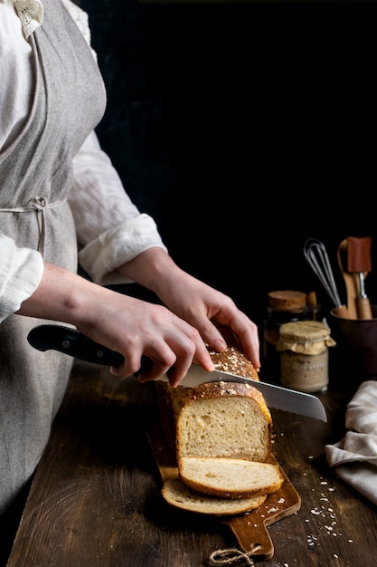 Foto cerca de manos femeninas cortando pan de masa madre integral casero