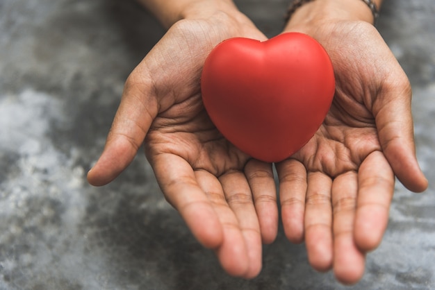 De cerca las manos femeninas dando corazón rojo como donante de corazón. San Valentín concepto de amor