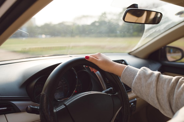 Foto cerca de manos femeninas en la dirección. chica viajera en viaje en coche, mirando la carretera. ver por encima del hombro