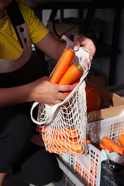 Foto cerca de manos femeninas empacando zanahorias