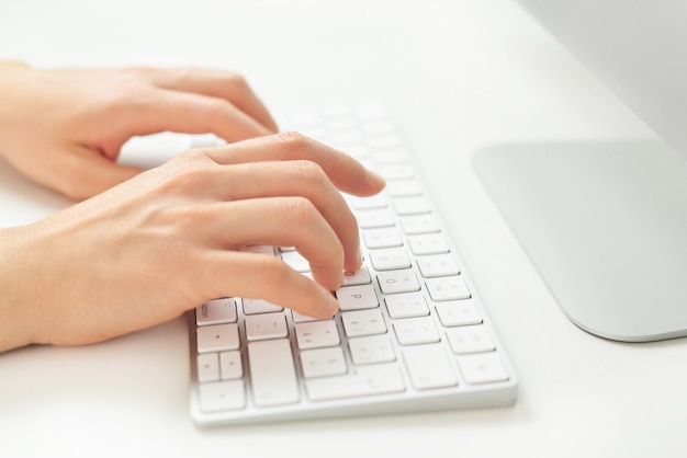 Cerca de manos femeninas escribiendo en el teclado de la computadora, empresaria trabajando en la oficina y usando la computadora.