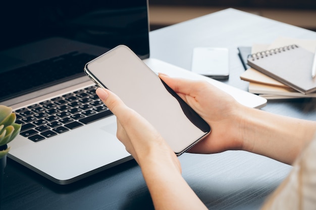 Cerca de manos femeninas con smartphone en la mesa de oficina