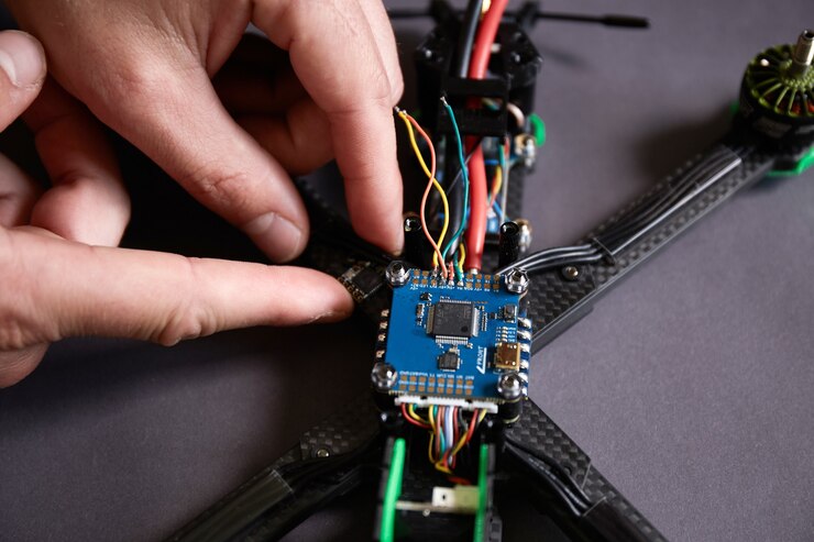 Foto cerca de las manos del hombre ensamblando un dron a partir de piezas, utilizando herramientas, preparando quadcopter de carreras de alta velocidad para el vuelo. reparar el dron antes del proceso de entrenamiento.