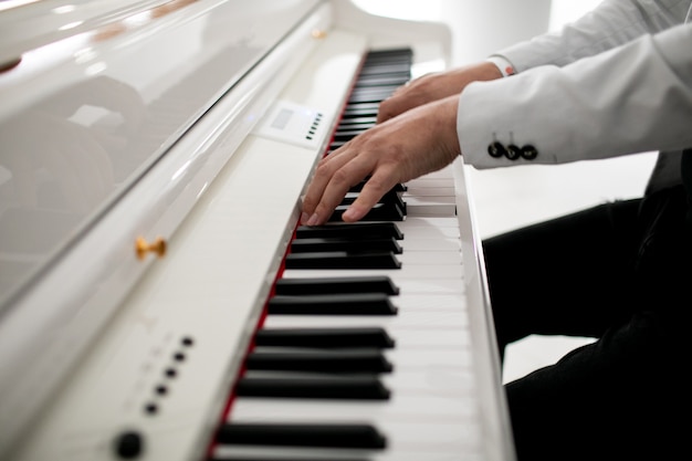 Cerca de las manos del hombre piano tocando las manos del pianista masculino en el teclado del piano de cola