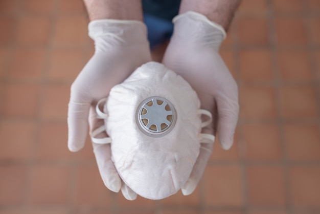 Foto cerca de las manos con una mascarilla médica para protección