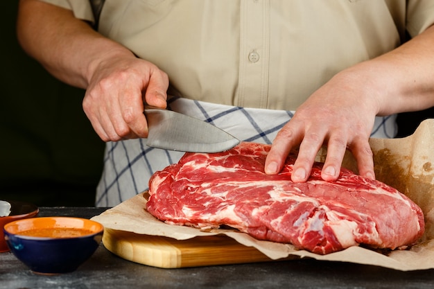 Cerca de manos masculinas cuchillo para picar carne de cerdo