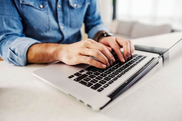 Cerca de manos masculinas escribiendo en la computadora portátil