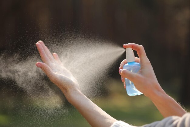 Foto cerca de las manos de la mujer aplicando spray de alcohol o spray antibacteriano al aire libre para evitar la propagación de gérmenes bacterias y virus tiempo de cuarentena centrarse en las manos cercanas coronavirus