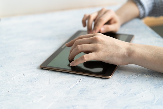 Foto cerca de las manos de la mujer escribiendo información de texto en un dispositivo de tableta digital