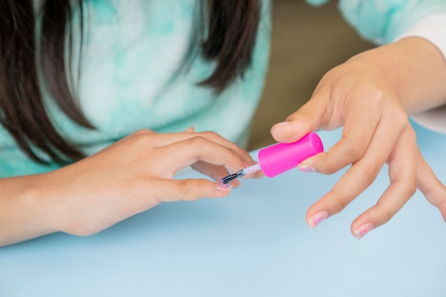 Cerca de las manos de una mujer joven pintándose las uñas con un barniz y copiando espacio