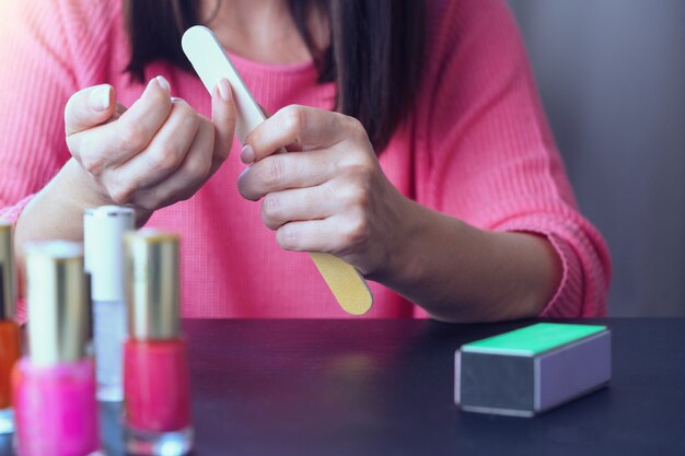 Foto cerca de las manos de una mujer joven que hace un hogar de manicura.