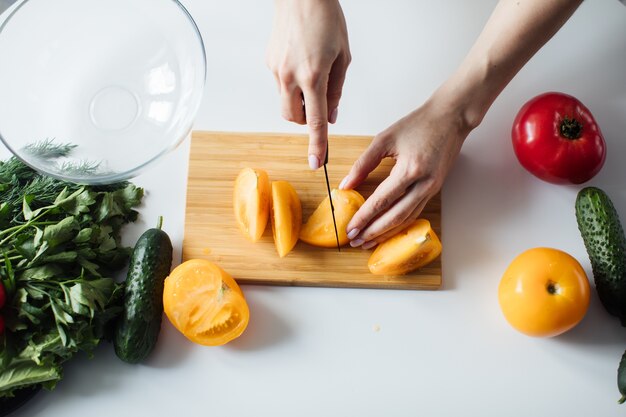 Cerca de las manos de una mujer que corta verduras para ensalada