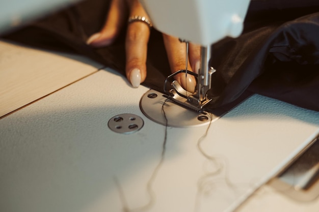 Cerca de manos. Mujer sastre trabajando en máquina de coser.