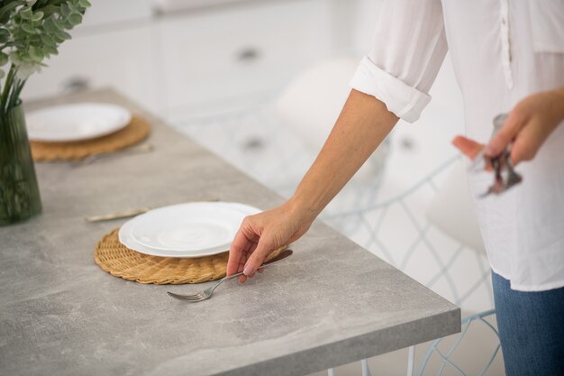 Cerca de las manos de la mujer sirviendo la mesa para la cena