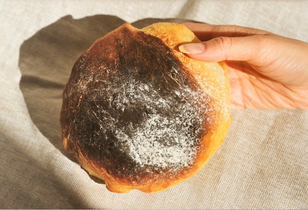 Foto cerca de las manos de una mujer sosteniendo pan recién horneado en casa.