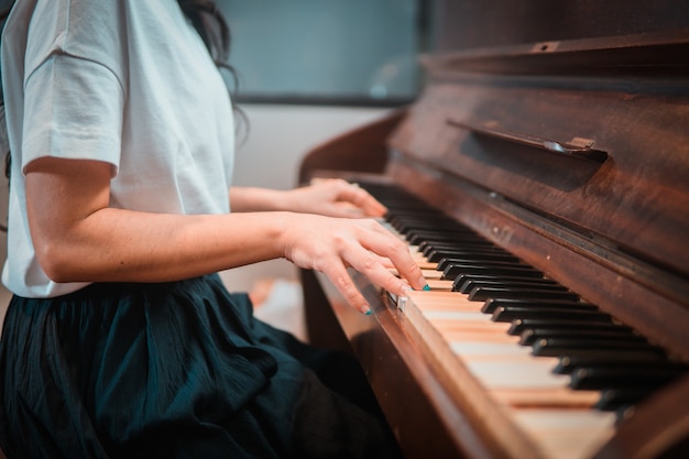 Cerca de manos de mujer tocando el piano