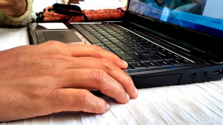 Foto cerca de las manos de la mujer usando su computadora portátil en casa