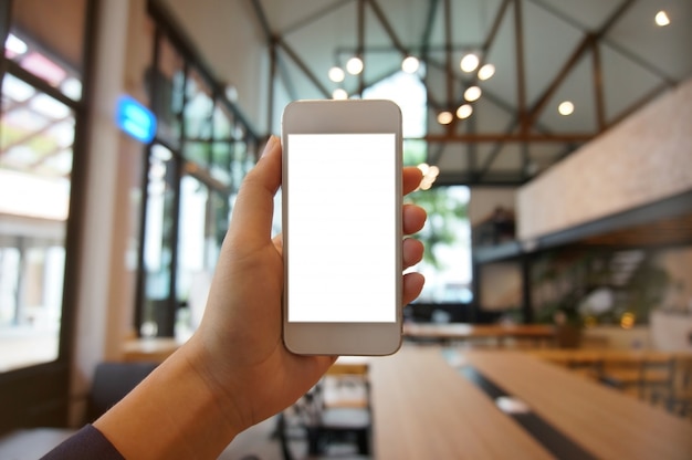 Cerca de las manos de las mujeres la celebración de teléfono celular en blanco copia espacio pantalla. teléfono inteligente con el concepto de tecnología