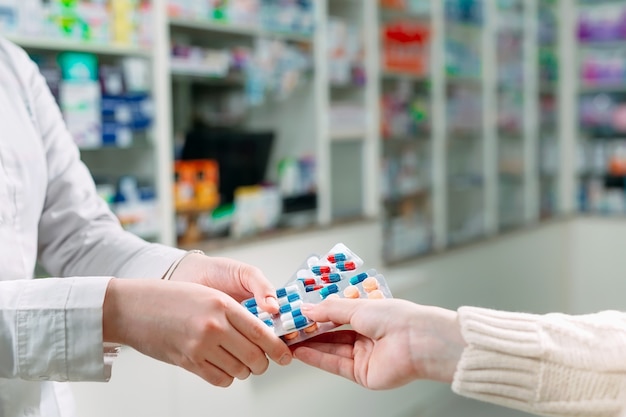 Cerca de las manos de una niña comprando pastillas en una farmacia