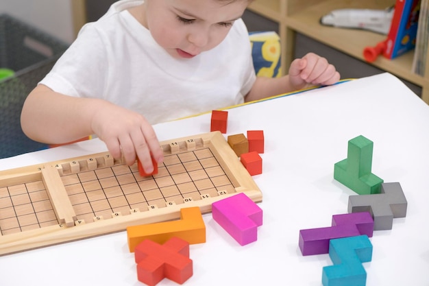 Cerca de las manos del niño jugando con coloridos ladrillos de madera en la mesa