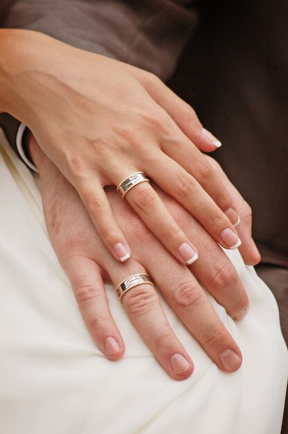 Cerca de las manos de la novia y el novio con anillos de boda