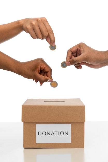 cerca de las manos poniendo monedas en la caja de donación