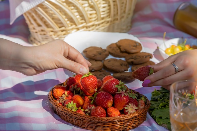 Cerca de manos tomando fresas en un picnic en el parque