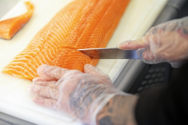 Cerca de mans manos cortando pescado en una tabla para cortar