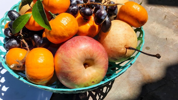 Cerca de manzanas, peras, uvas y naranjas en cesta verde 01