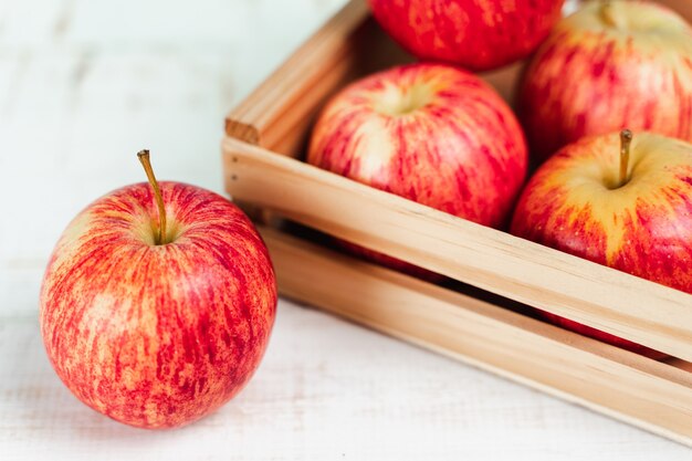 Cerca de manzanas rojas maduras frescas en una caja de madera.