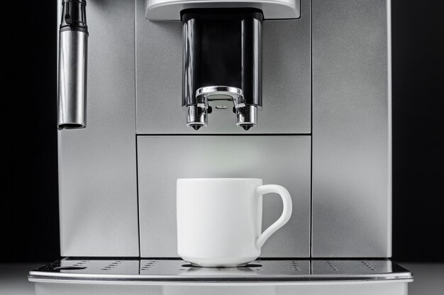 Foto cerca de la máquina de café moderna y taza blanca