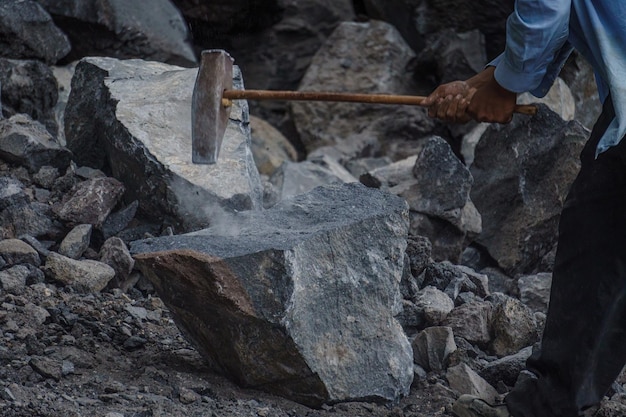 Foto cerca de un martillo de metal golpeando una roca volcánica