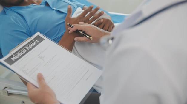 Foto cerca del médico sentado al lado de la cama de un paciente masculino en el hospital