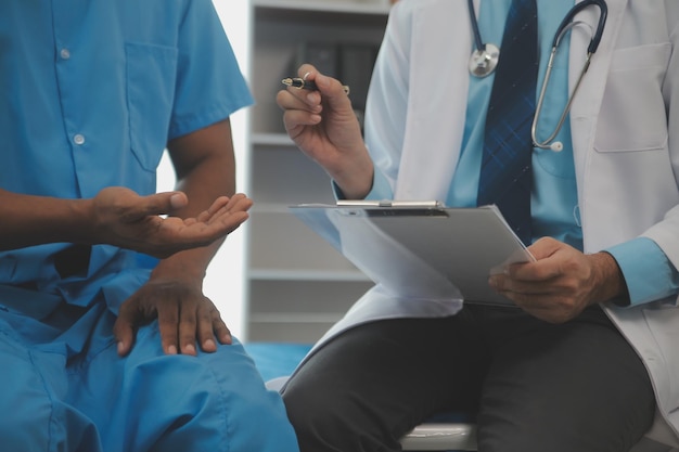 Cerca del médico sentado al lado de la cama de un paciente masculino en el hospital