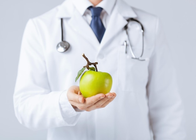 Cerca del médico varón con manzana verde