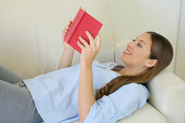 Cerca de mentir libro de lectura de mujer descansando en el sofá en casa