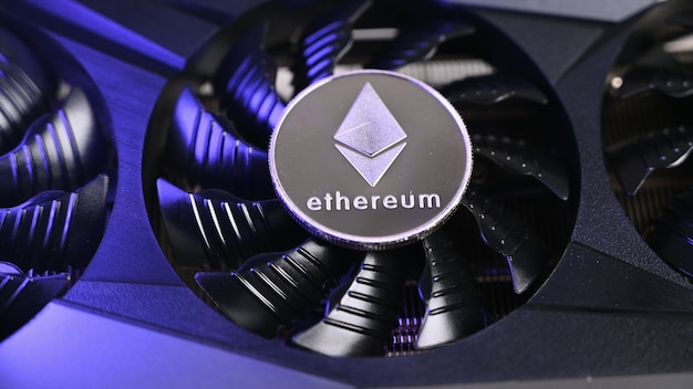 Cerca de la moneda Ethereum en una tarjeta de video negra iluminada por luz azul. Concepto de minería Ethereum.