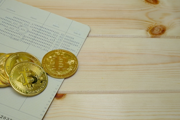 Cerca de monedas bitcoin de oro en la libreta bancaria en la mesa de madera