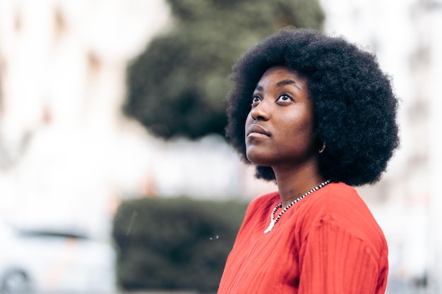 Cerca de una mujer africana soñadora mirando al cielo