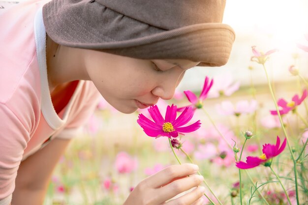 Cerca de mujer alegre que huele con flor de cosmos en el jardín.
