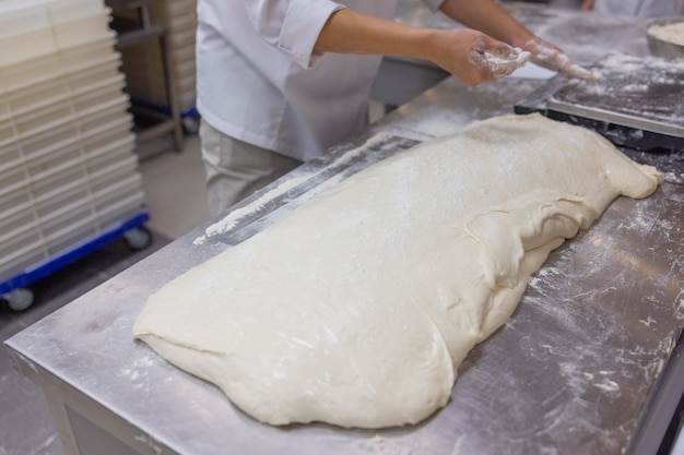 Cerca de la mujer amasando la masa de pizza.