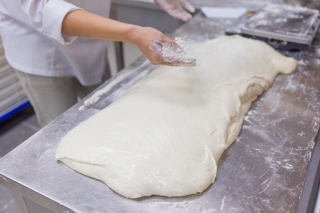 Cerca de la mujer amasando la masa de pizza.