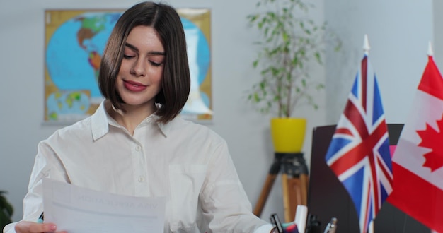 Cerca de una mujer atractiva trabaja en una agencia de viajes en una computadora portátil sentada en una mesa en el fondo de un mapa mundial Concepto de viaje