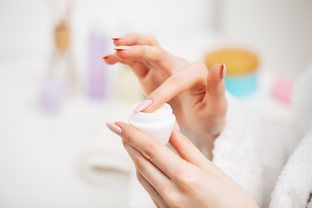 Cerca de mujer con crema hidratante para el cuidado de la piel facial